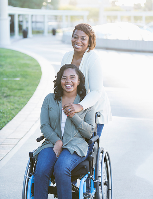 Image of a girl in a wheelchair and her mom with him